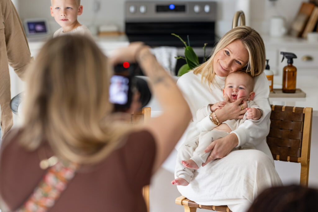 Behind the scenes in-home newborn photography session with mom and baby in bright kitchen