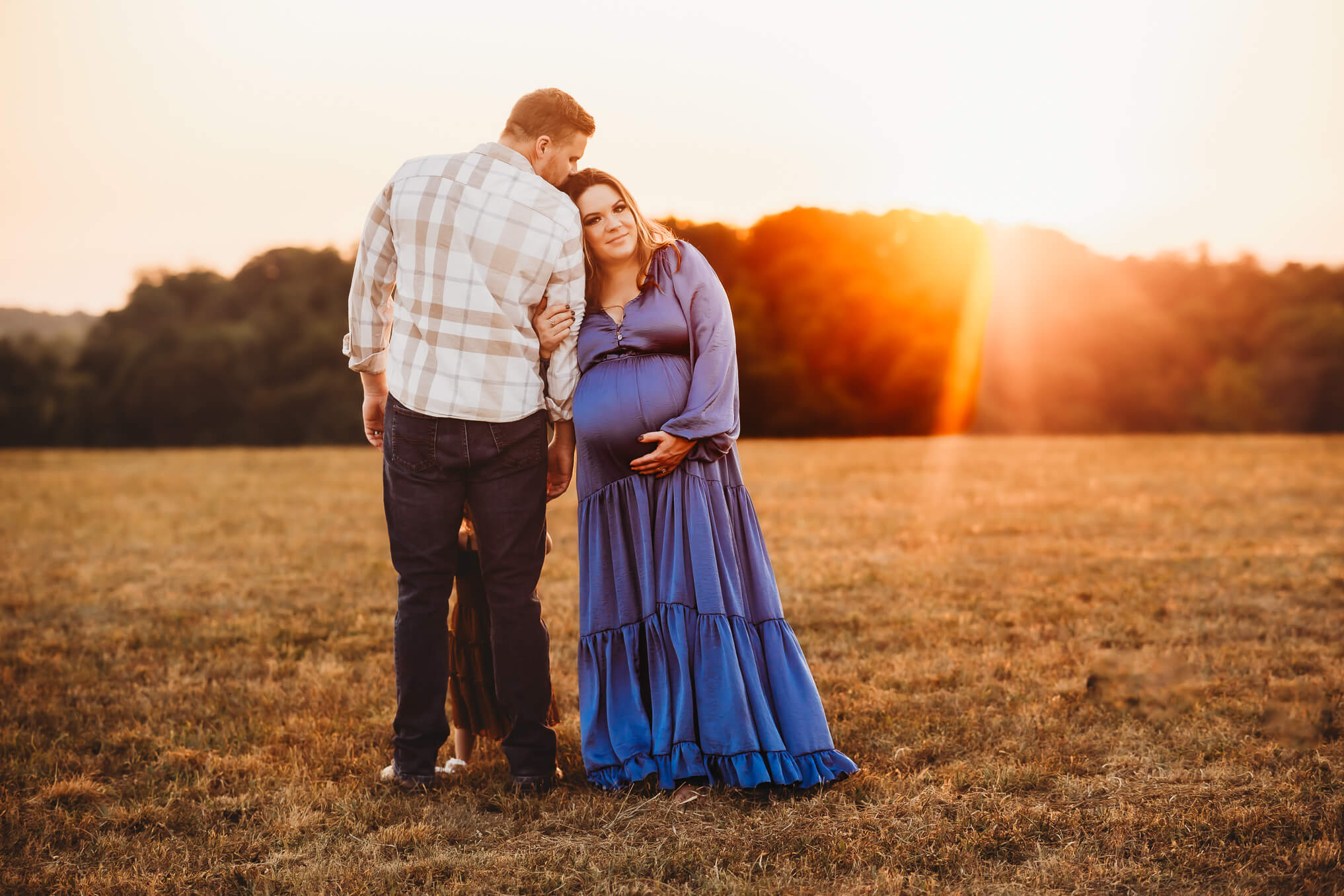 Husband and wife in sunset glowing maternity photo