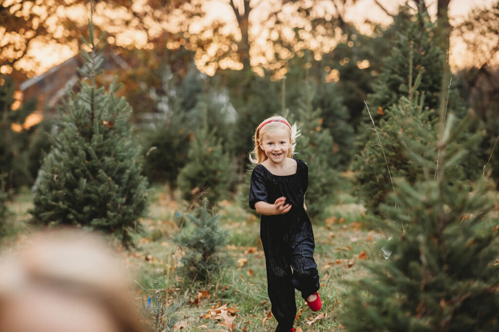 Girl smiling and running through the field at a Christmas Tree Farm around Harrisburg 