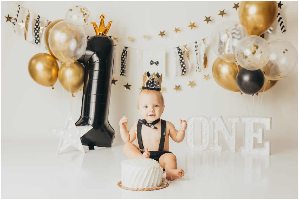 Black and gold balloons, gold stars, and a baby as the star of this first birthday show. 