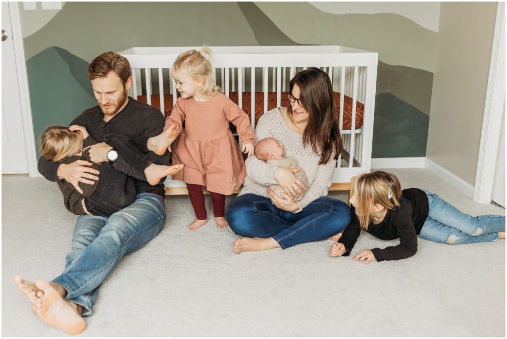 Mom, dad, their three daughters, and their newborn baby boy taking a candid family photo as part of their Harrisburg newborn session