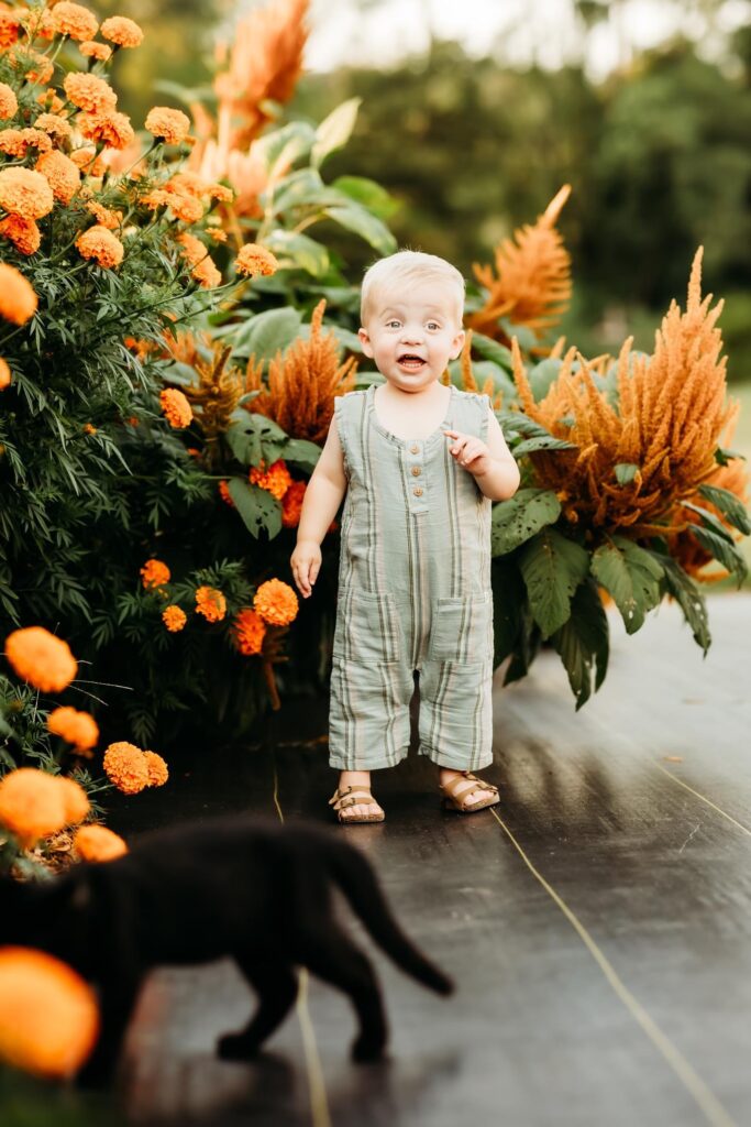 Little boy smiling happily in front of beautiful flowers during Harrisburg family photos