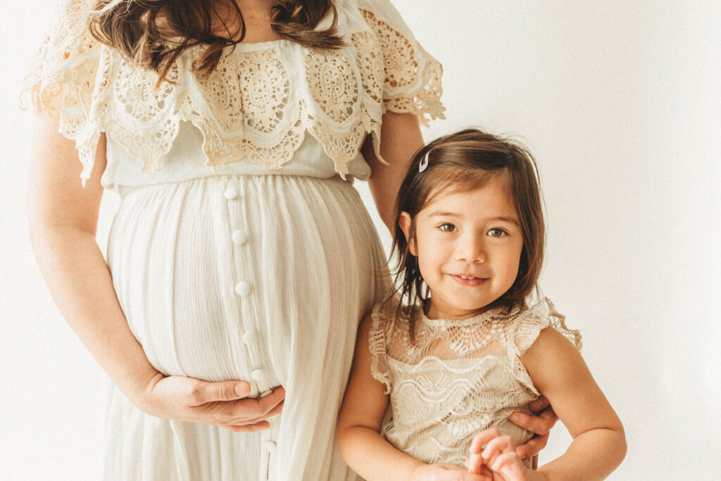 little girl standing next to her mom's pregnant belly just one way to announce her pregnancy