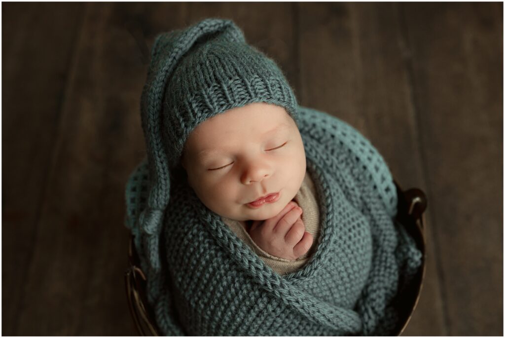 Harrisburg newborn session baby boy in a blue swaddle and matching sleepy cap with puckered lips. 