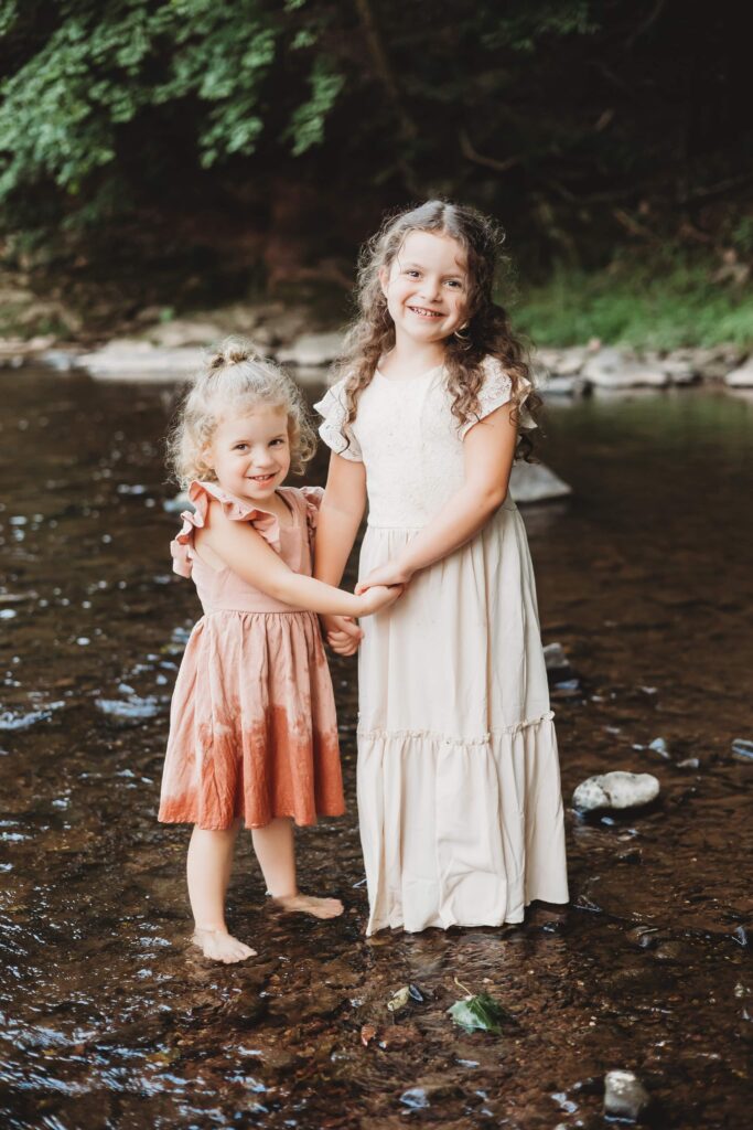 Sisters spending the summer together playing in a creek