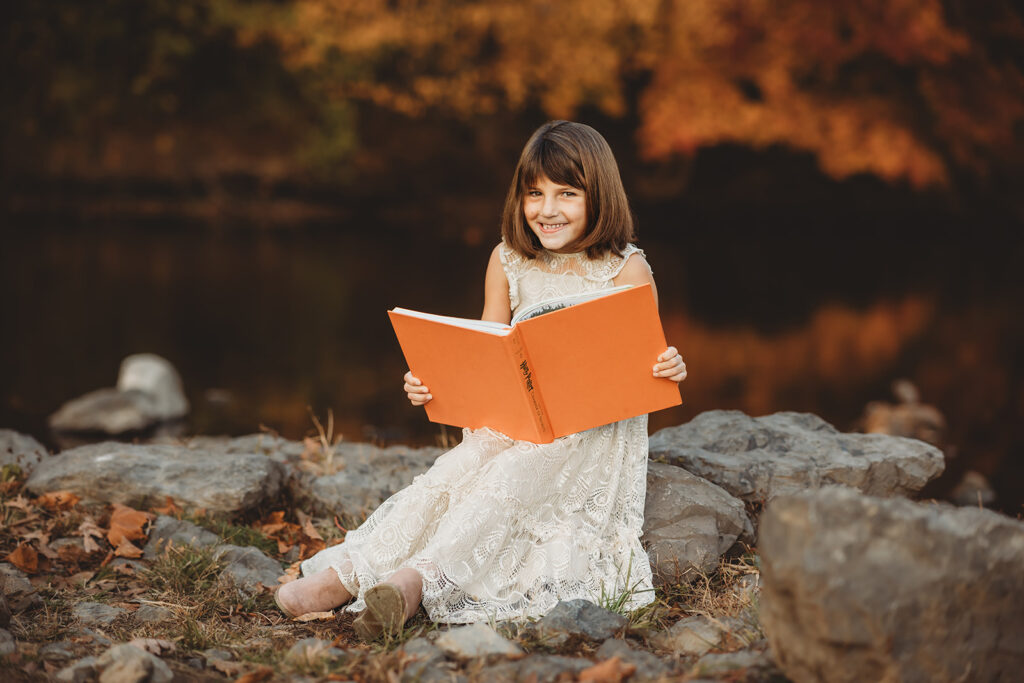 Little girl smiling and reading a Harry Potter book