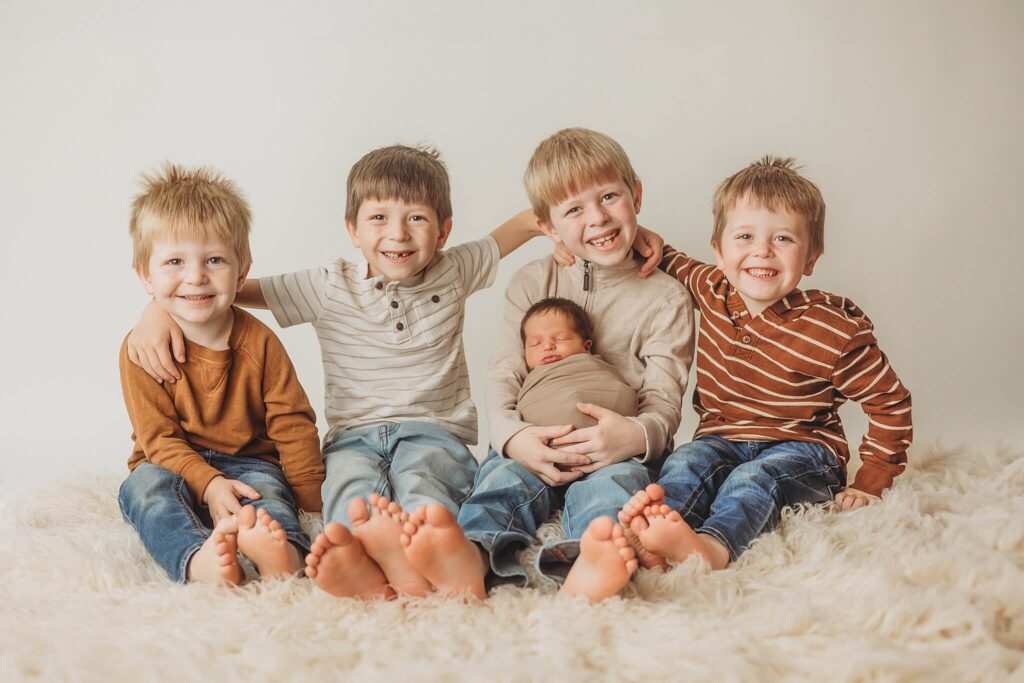 York newborn photo session with four older brothers holding their swaddled newborn baby brother