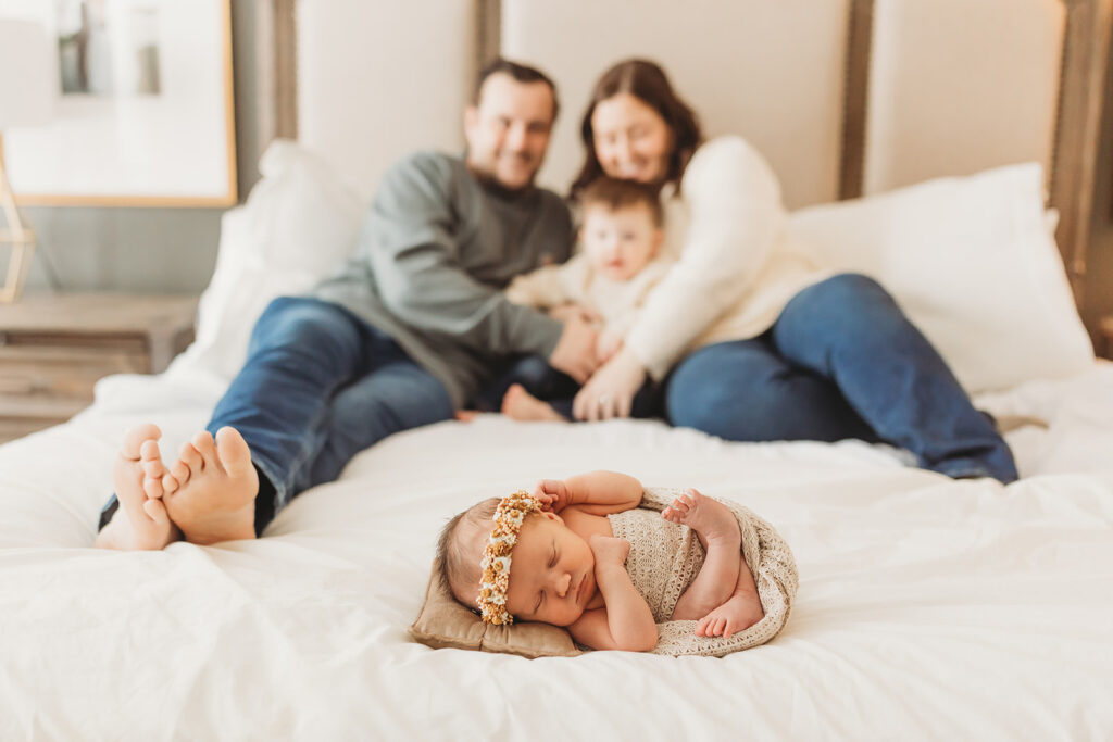 Baby girl is the star of the show as this family of four cuddles together in bed during their newborn session at home in York
