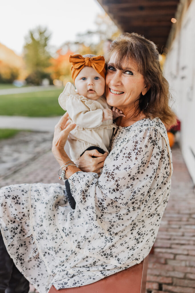 Grandmother in a floral dress holding her granddaughter in fall photos in Harrisburg, PA