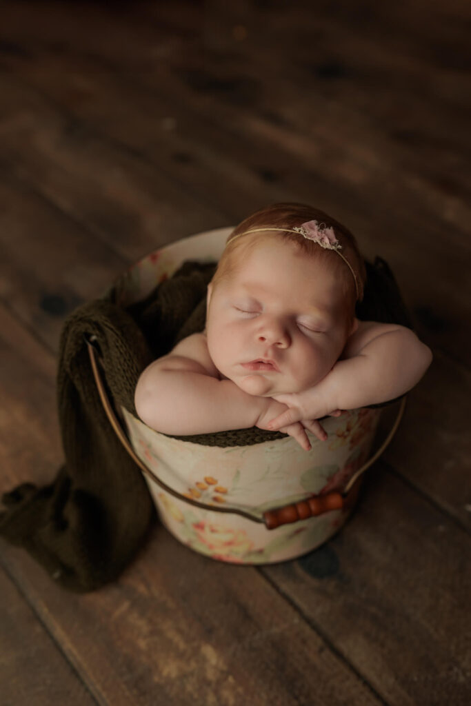 Baby girl posed gently in a floral bucket during her york, pa studio newborn session