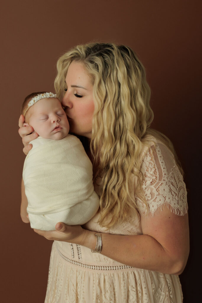 New mom giving her baby girl a sweet kiss during their family portion of their newborn session in york