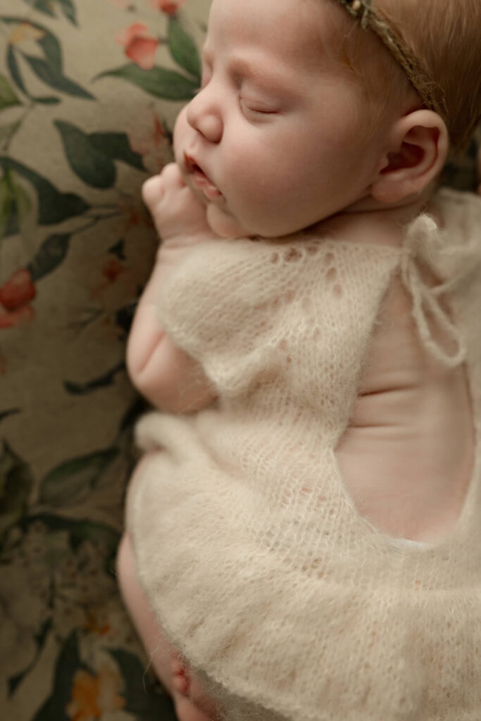 Newborn baby girl sleeping soundly with her adorable back rolls showing