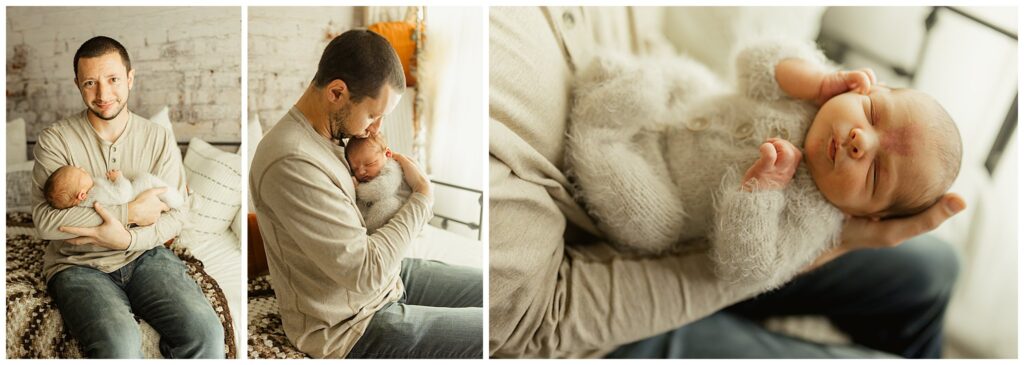 Newborn baby boy in a fuzzy romper snuggled by his dad, sitting on a bed. 