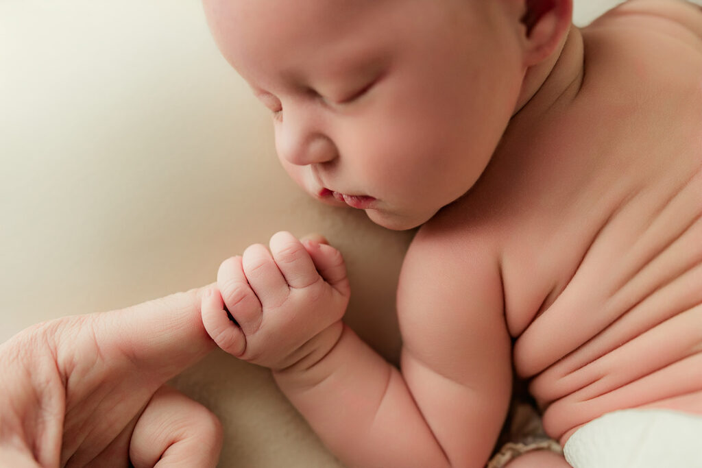 Tiny baby hand wrapped around her dad's during mechanicsburg newborn photography session