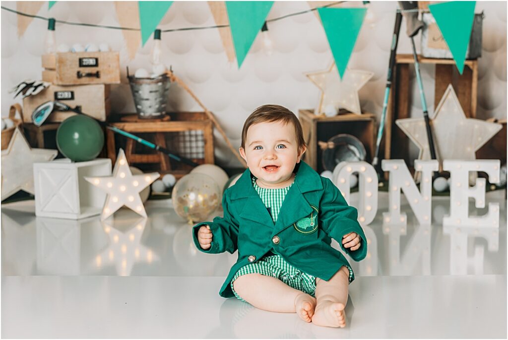 All smiles in his tiny baby sized Master's Jacket for his hole in one themed cake smash
