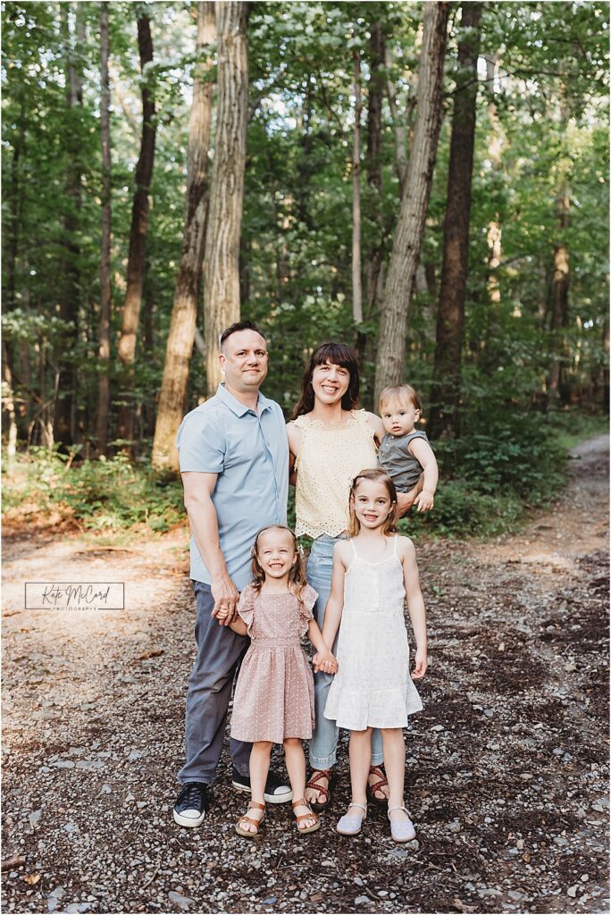 Family standing on a wooded path posed and smiling for a classic Christmas card portrait in Harrisburg PA