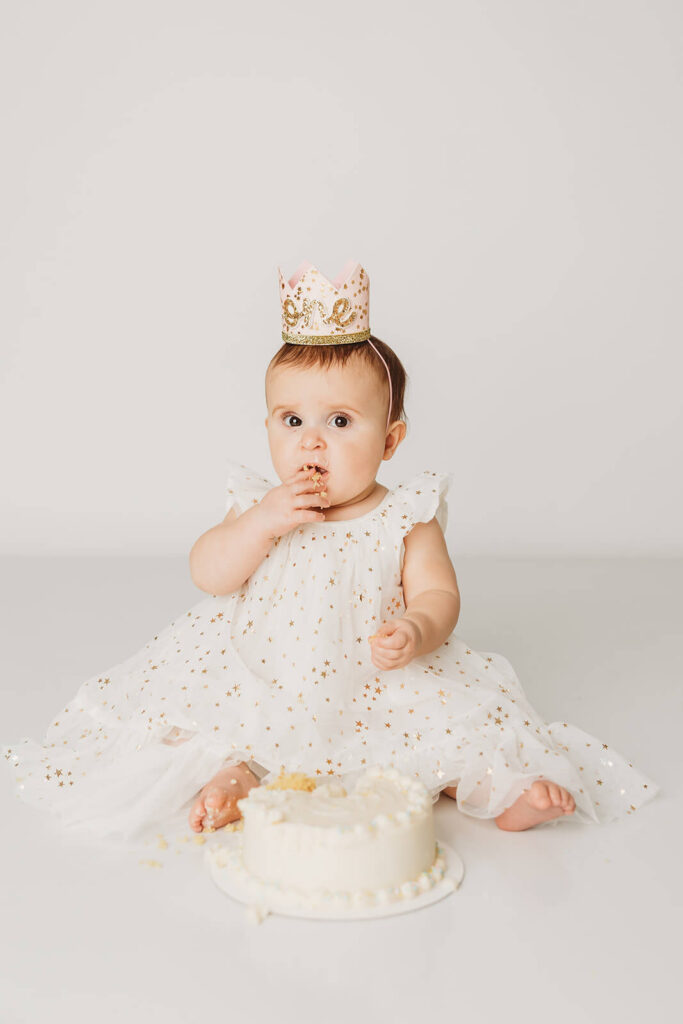 Baby takes a small bite of her first birthday cake at her cake smash session in mechanicsburg 