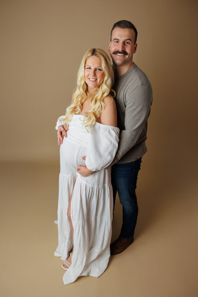 Studio maternity portrait with warm tan backdrop photographed in Dover PA