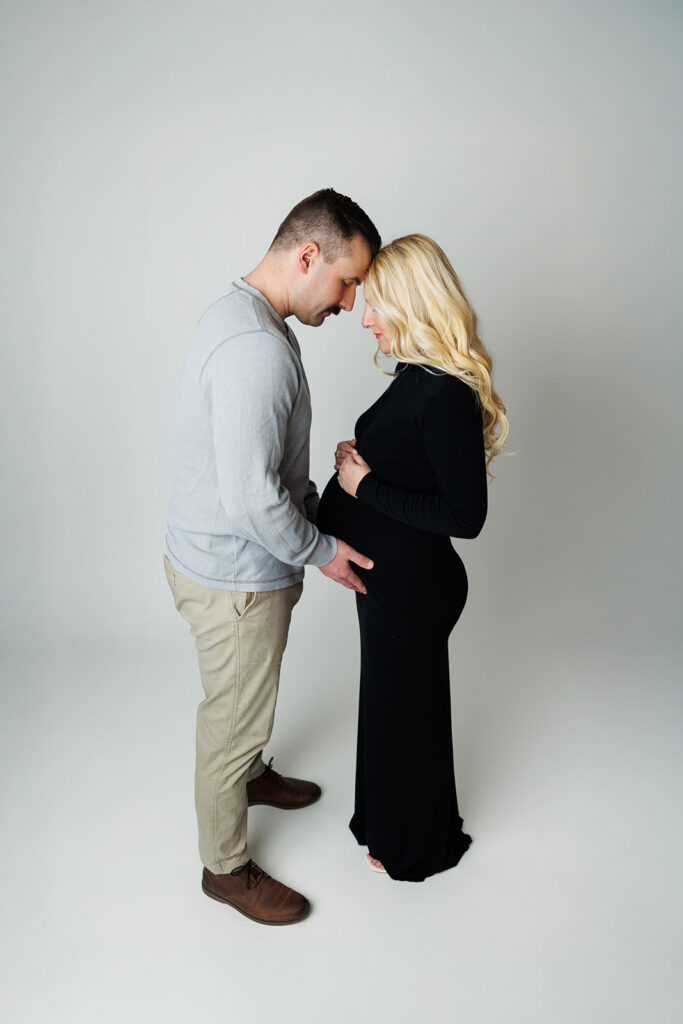 Intimate maternity portrait of couple touching foreheads during studio session
