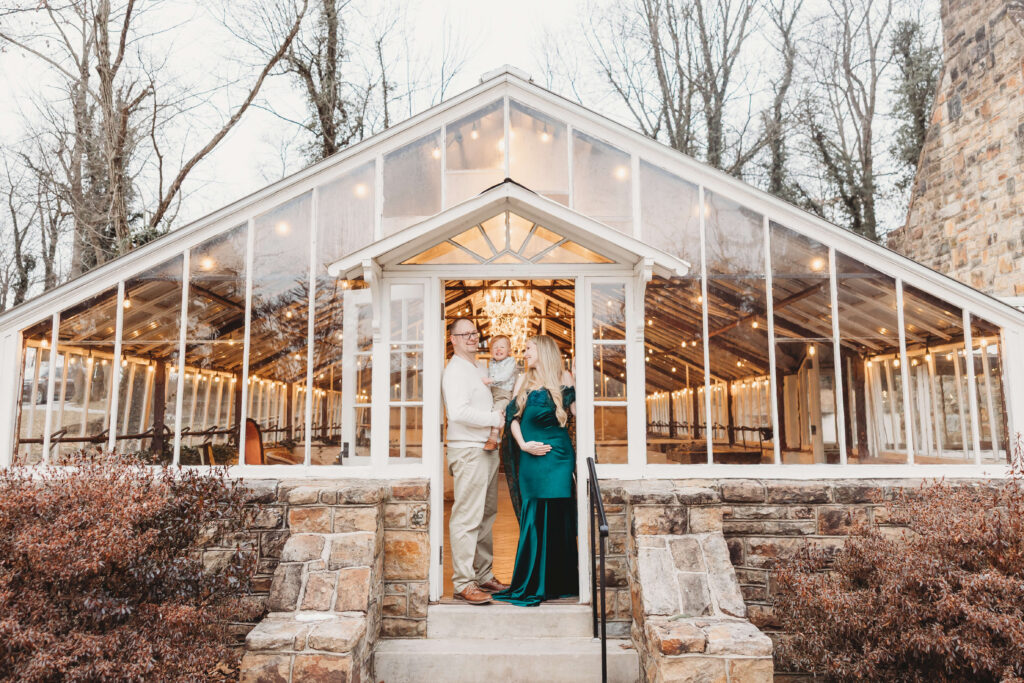 Family framed in the doorway of the Historic Shady Lane greenhouse, capturing a cozy maternity session at Historic Shady Lane before snowfall.