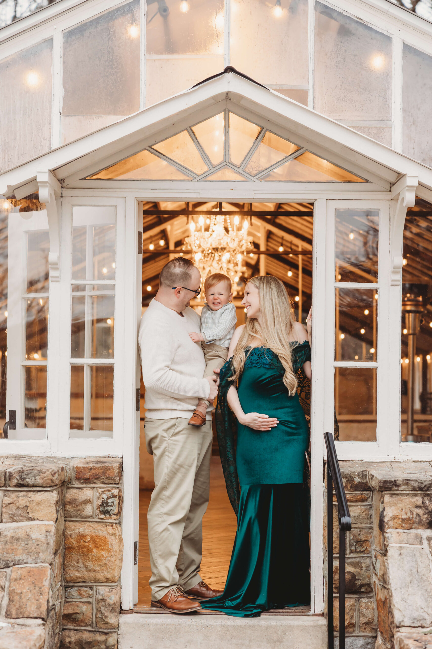 Family framed in the doorway of the Historic Shady Lane greenhouse, capturing a cozy maternity session at Historic Shady Lane before snowfall.