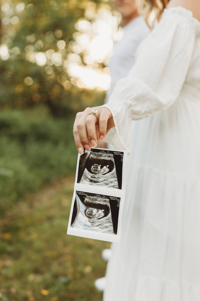 Expecting mother holding ultrasound photo during early prenatal appointment