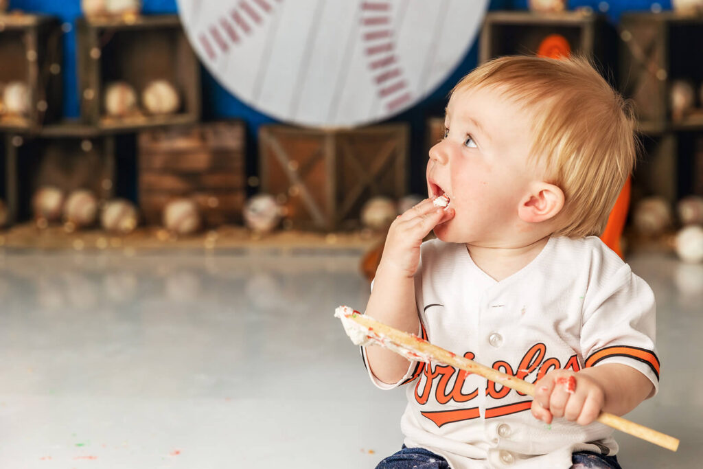 Baby boy in Orioles jersey eating cake with bat during Orioles baseball cake smash York PA session
