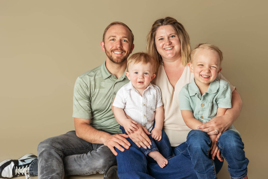 Family portrait at cake smash session in York PA with parents, big brother, and one-year-old baby boy on neutral backdrop