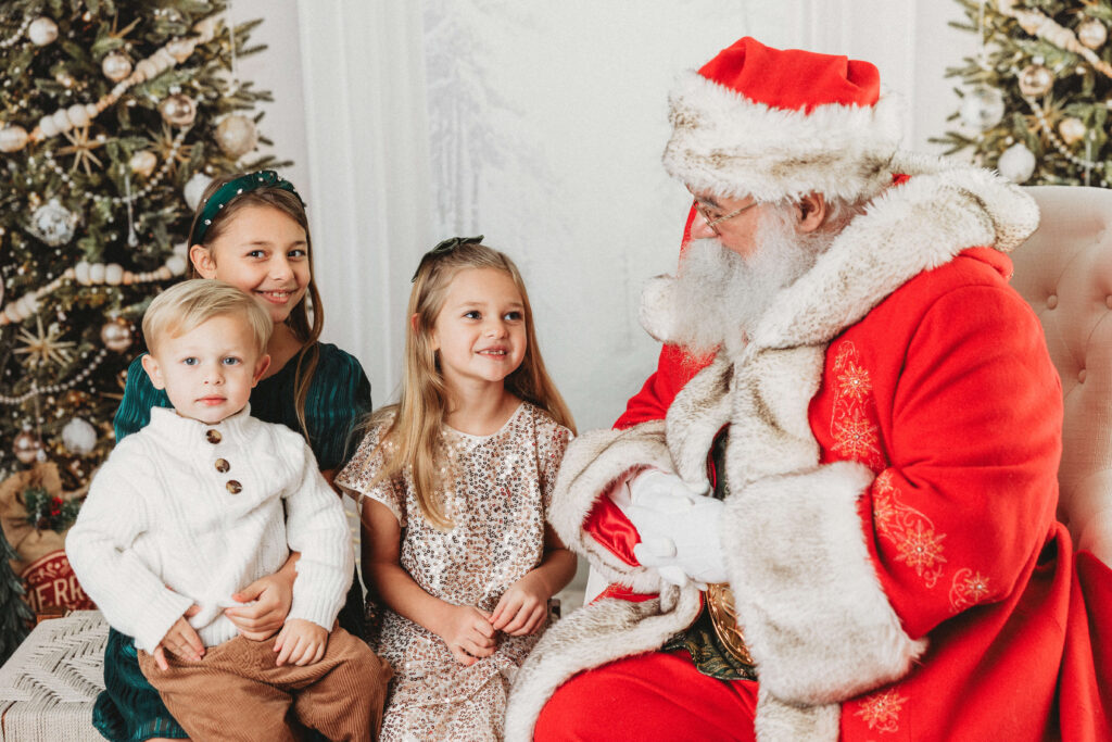two sisters and their little brother sit together as they tell santa what they want for christmas