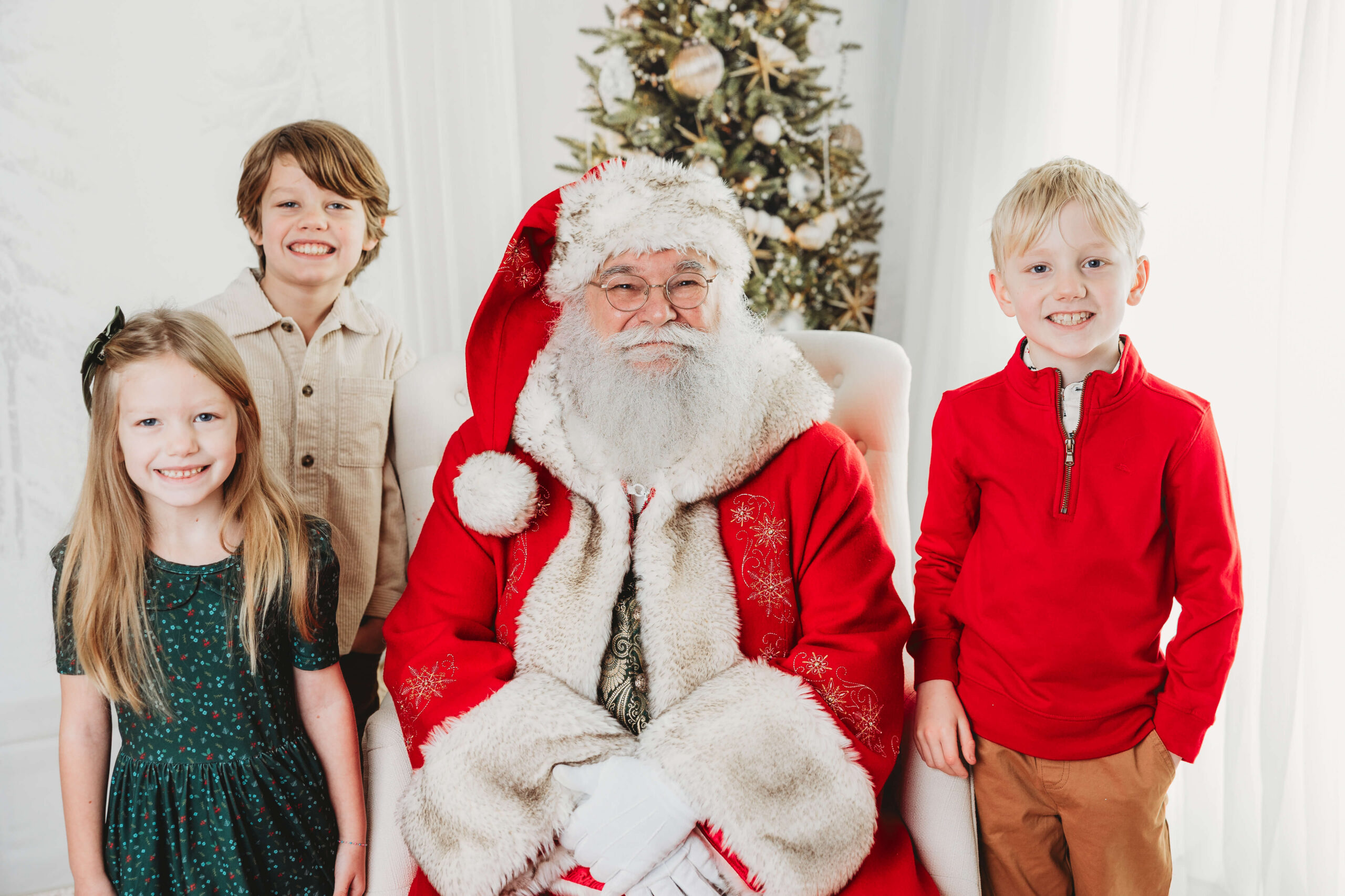 Brothers and their sister smile for a photo with Santa during their York, PA Santa photoshoot