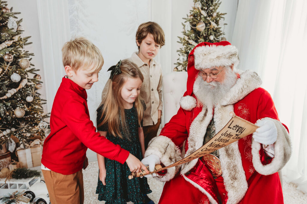 siblings find their names on santa claus's nice list during the santa photography session