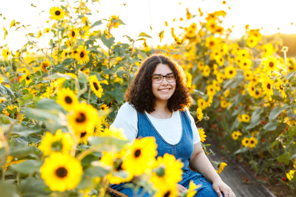 Central PA senior session surrounded by bright yellow sunflowers at Royal Oaks Farm in Lebanon PA