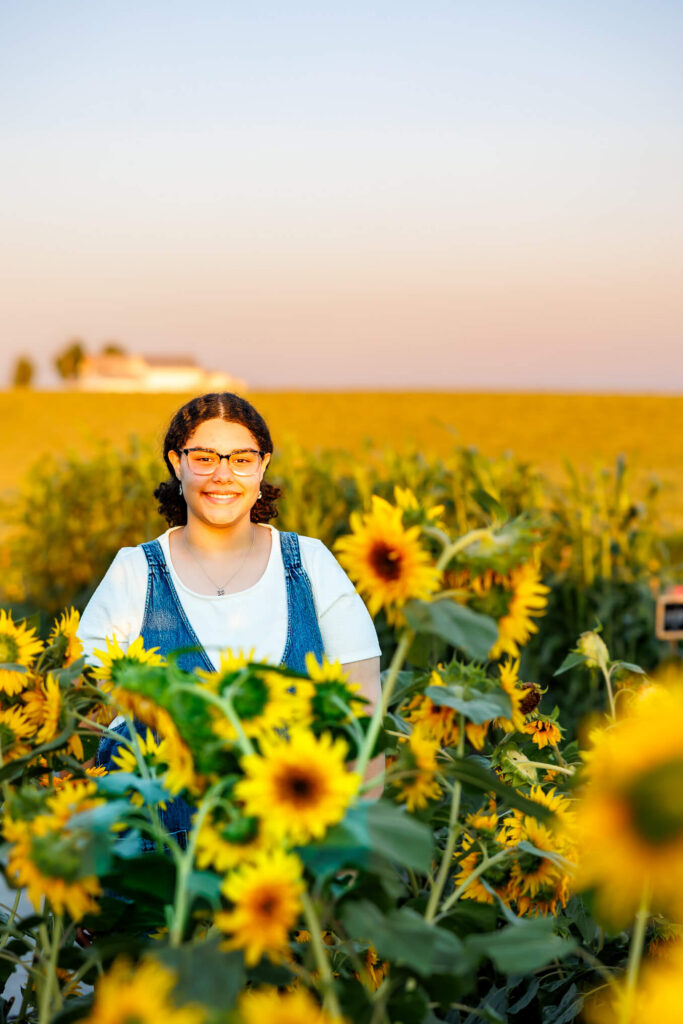 Senior girl standing among blooming sunflowers during her summer senior photos in Lebanon Pennsylvania
