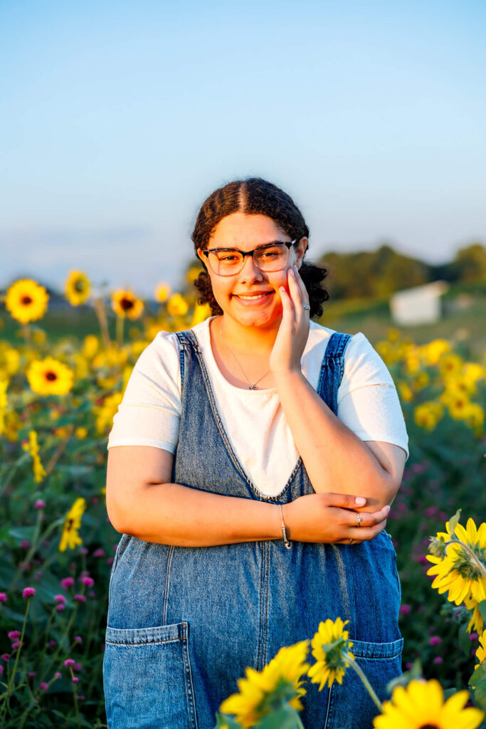 Senior girl holding a sunflower in a blooming field during her Central PA senior session