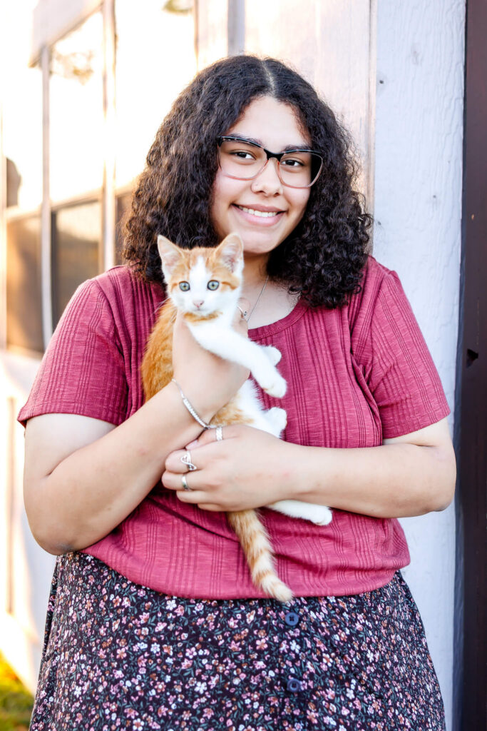 Senior girl holding a farm kitten during her flower farm senior session in Lebanon Pennsylvania