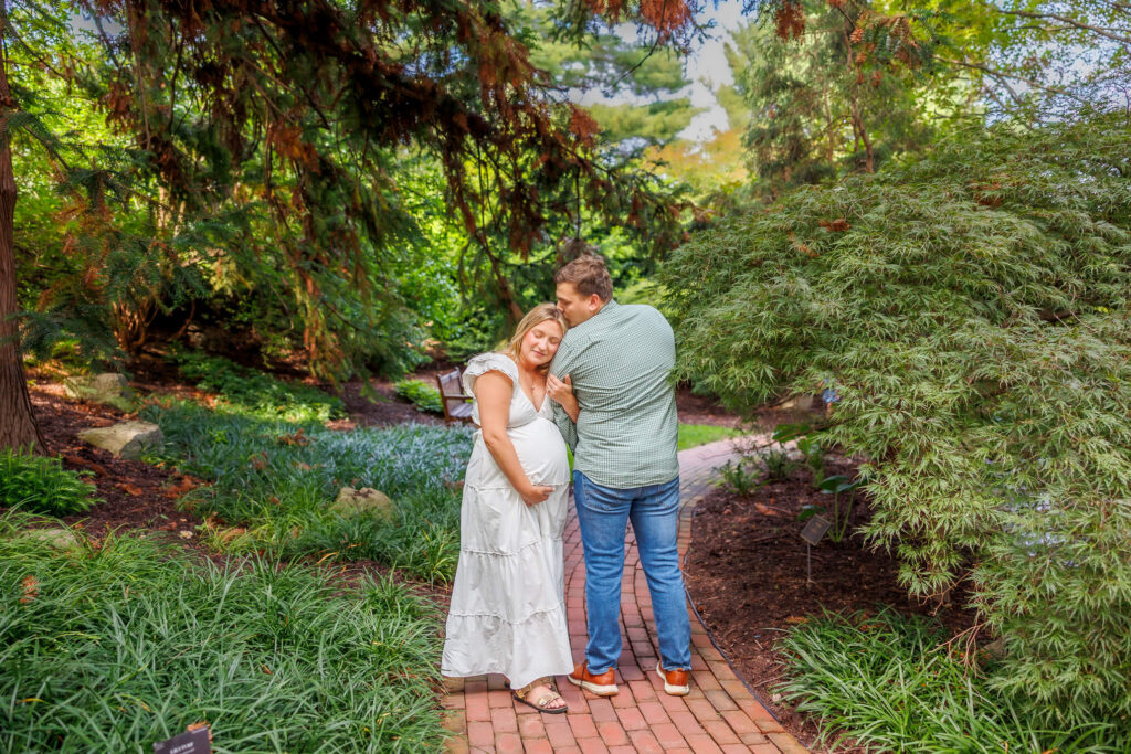 Couple embracing on a garden path during their Hershey Gardens maternity photos in Hershey, PA.