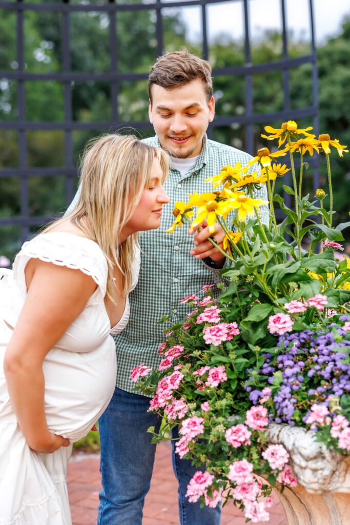 Expecting parents enjoying the colorful flowers together during their summer maternity photography session at Hershey Gardens.
