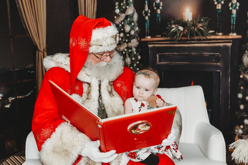 Baby reading a Christmas book with Santa during pictures with Santa in Central Pennsylvania