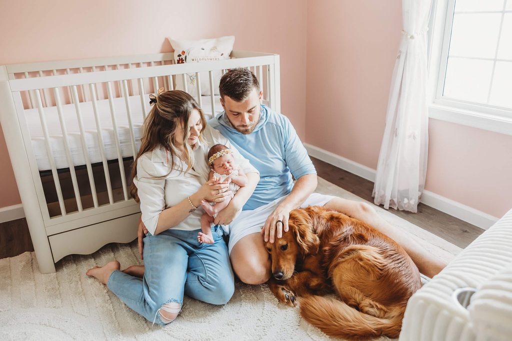 golden retriever lays gently with his family in the baby's nursery during their in home newborn session in central pa
