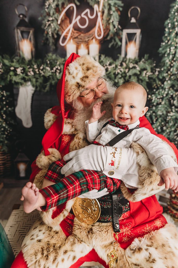 Smiling baby sitting with Santa during pictures with Santa in Central Pennsylvania.